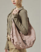 Close-up profile of model wearing a dusty pink star-studded soft faux leather crescent hobo bag