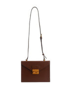 Front view product shot of a dark brown structured leather envelope flap shoulder bag with an adjustable strap and vintage gold push-lock closure on a white background.