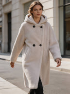 Street style shot of a woman walking in a cozy white hooded double-breasted plush shearling wool long coat.