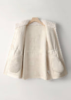 Interior suede lining detail of an off-white women's shearling coat on a wooden hanger.