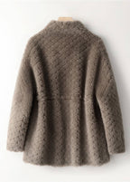 Back view of a taupe brown quilted shearling wool coat hanging on a wall.