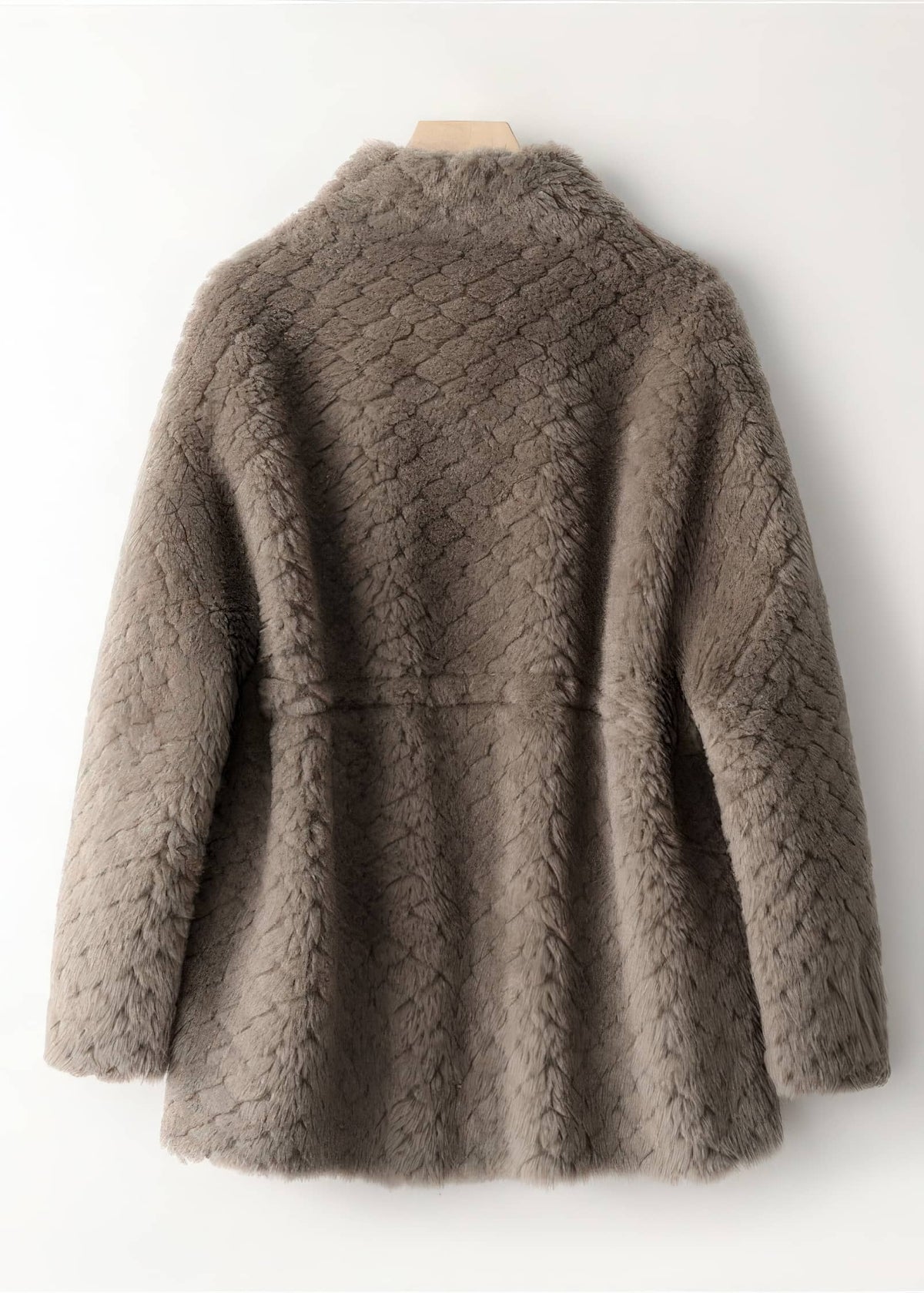 Back view of a taupe brown quilted shearling wool coat hanging on a wall.