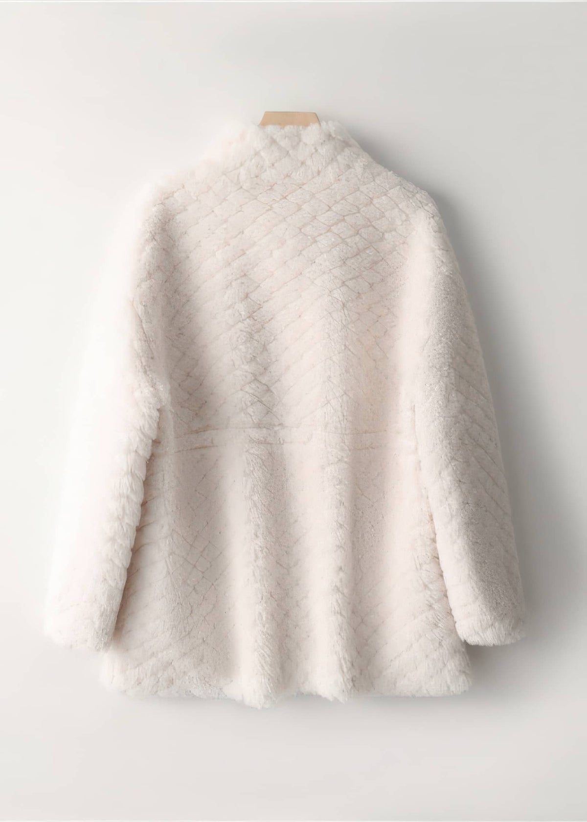 Back view of an off-white diamond lattice shearling wool coat hanging against a plain white background.