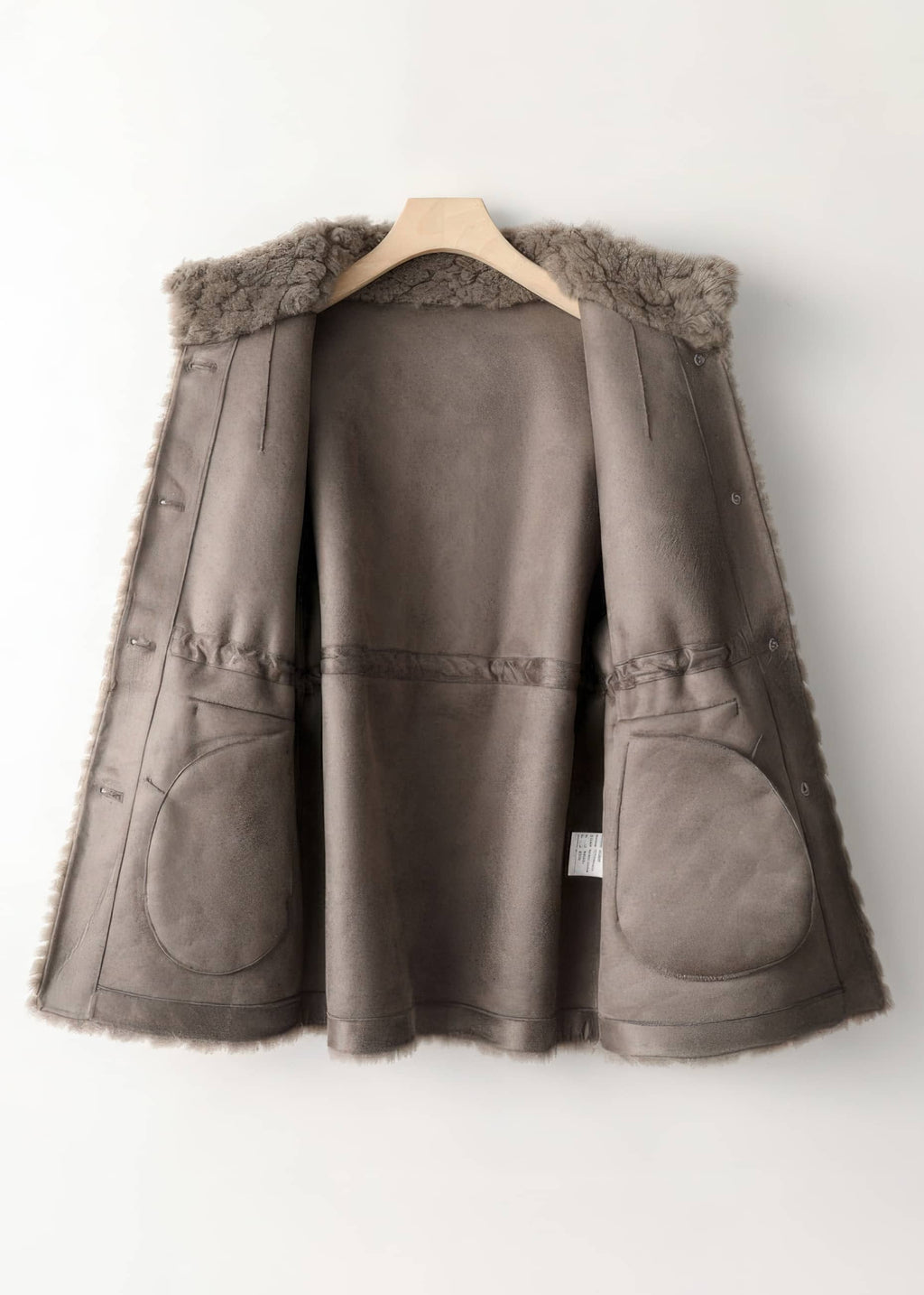 Interior view of a taupe brown faux suede lined winter shearling coat on a hanger.