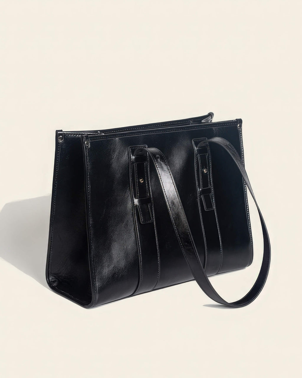 Perspective view of a structured black leather work tote bag for women featuring a glossy finish and minimalist design.