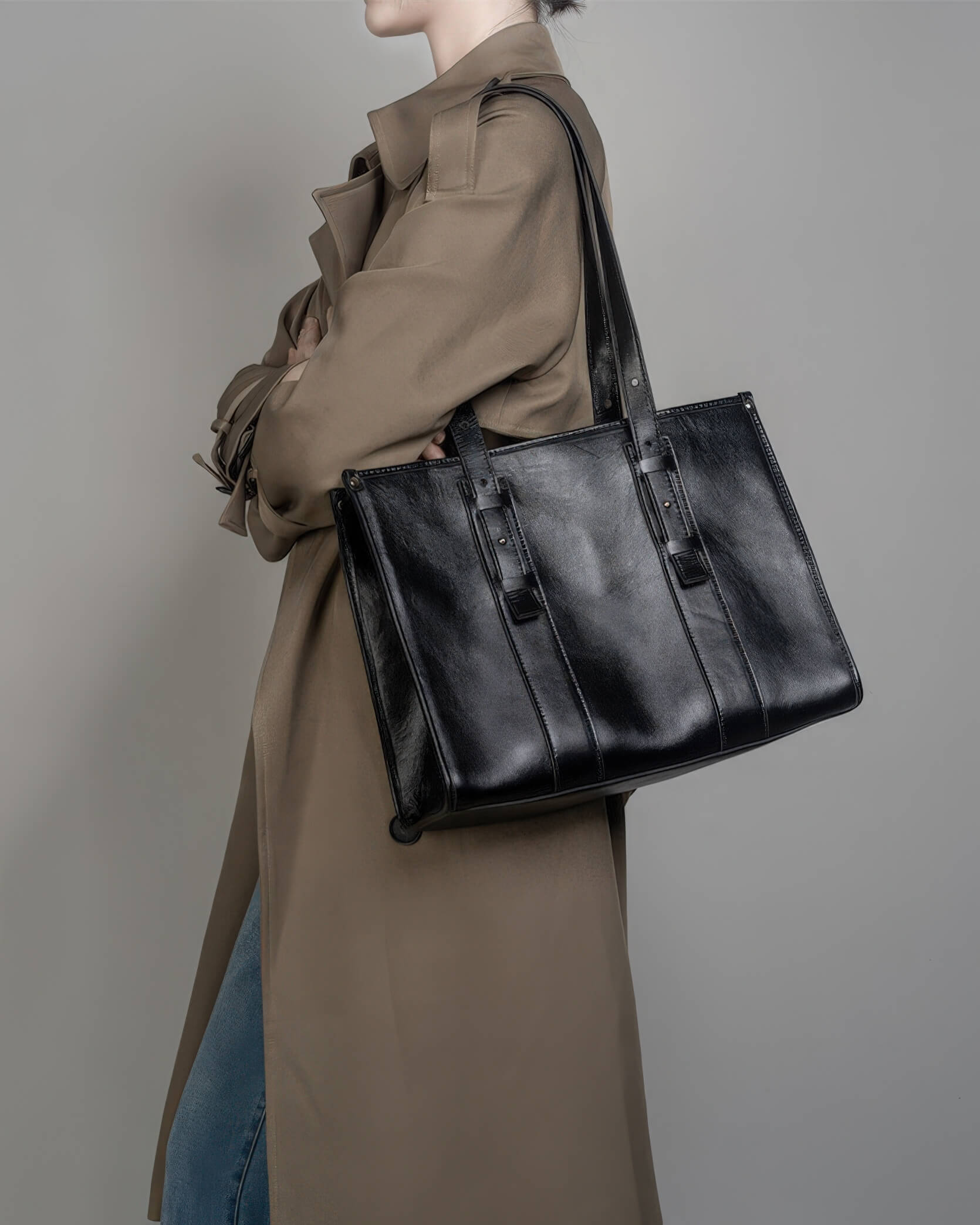 Professional lifestyle image of a black leather work tote bag for women with long adjustable straps and a structured design.
