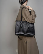 Back view of a woman wearing a black leather shoulder bag, demonstrating the bag's size and fit for daily work use.