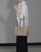 Side profile of a woman carrying a stylish grey leather laptop bag for work on her arm.