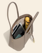 Interior of a large grey leather work tote bag filled with a laptop, tablet, and yellow umbrella.
