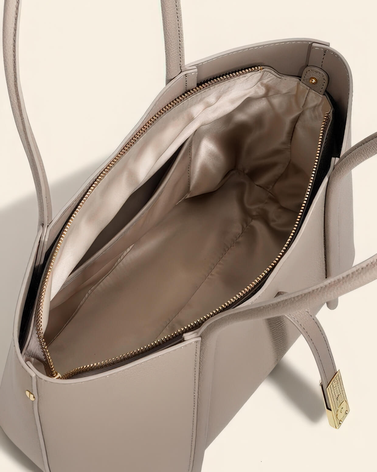 Close-up of the interior zip pocket and smooth lining of a high-quality grey leather work bag for women.