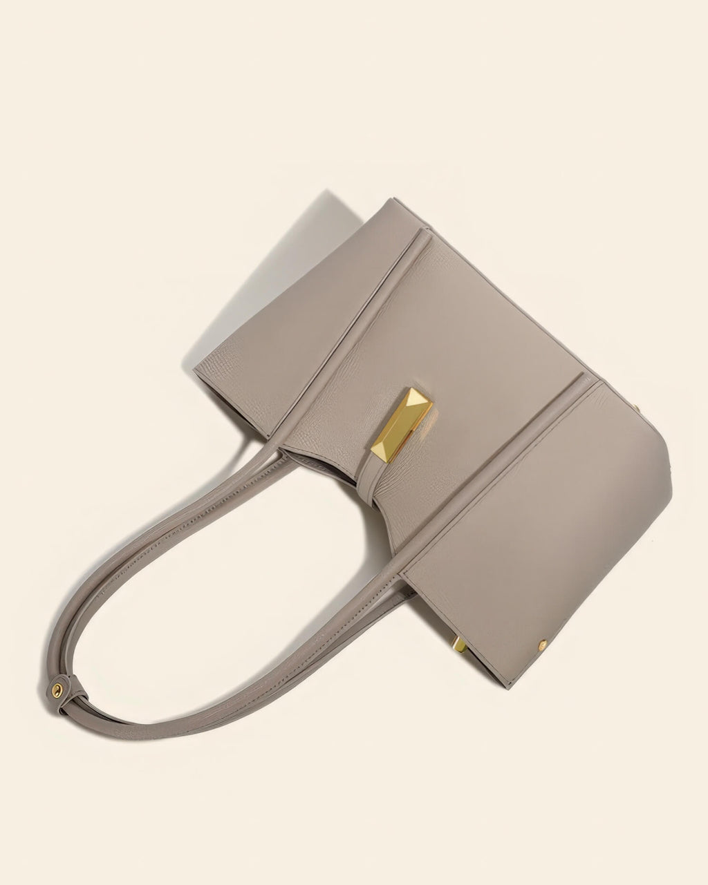 Front view of a minimalist grey genuine leather tote bag with long shoulder straps and a distinctive gold metal clasp.