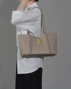 Professional woman carrying a spacious grey leather tote bag on her shoulder for a business casual look.
