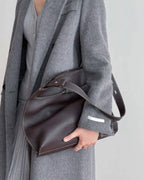 Model holding a vintage dark red distressed leather shoulder bag with a silver key charm.
