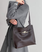 Close-up of a minimalist burgundy leather tote bag with elegant silver hardware details.