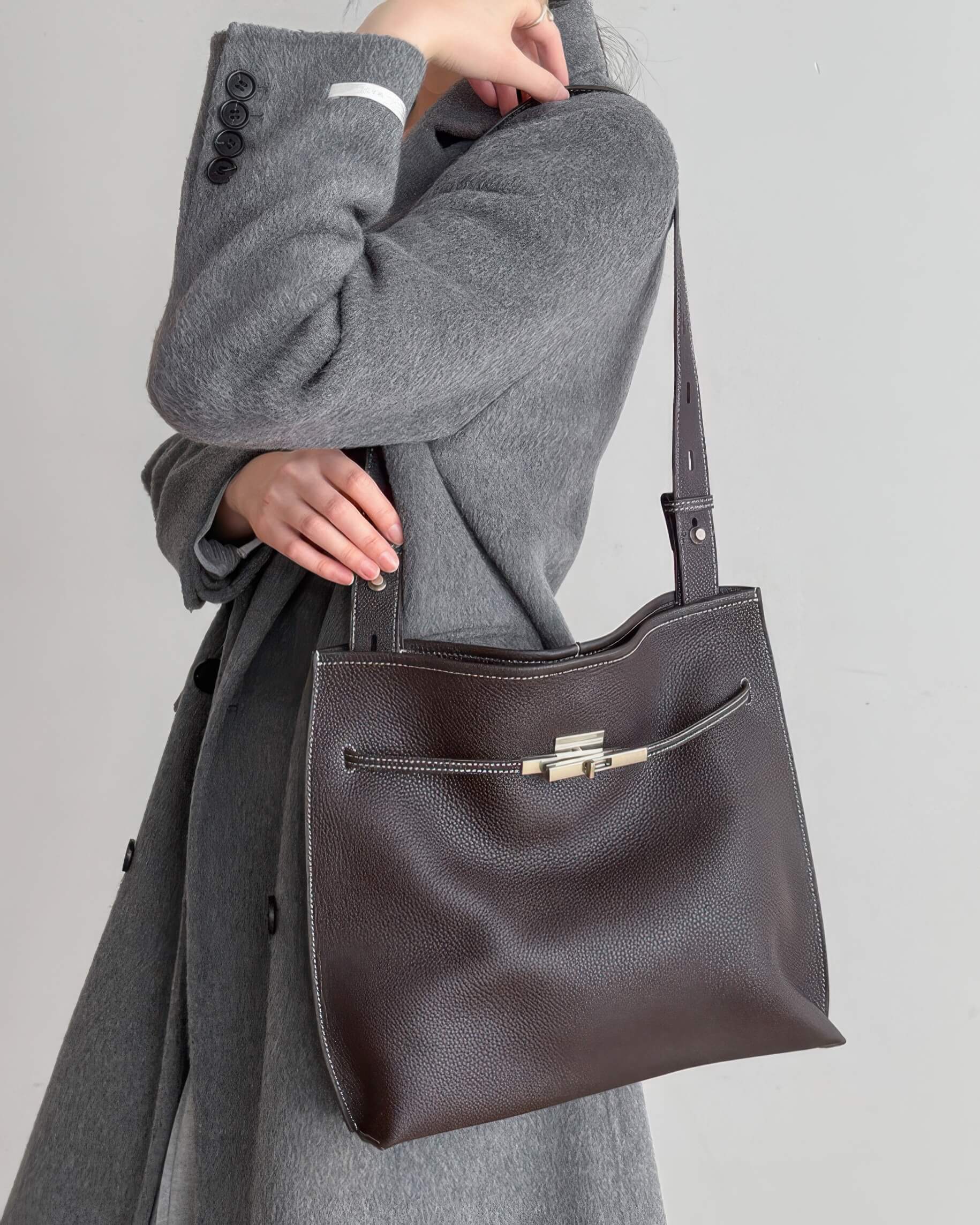 Close-up of a minimalist burgundy leather tote bag with elegant silver hardware details.