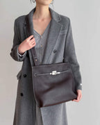 Street style shot of a model carrying a dark cherry leather briefcase-style bag.