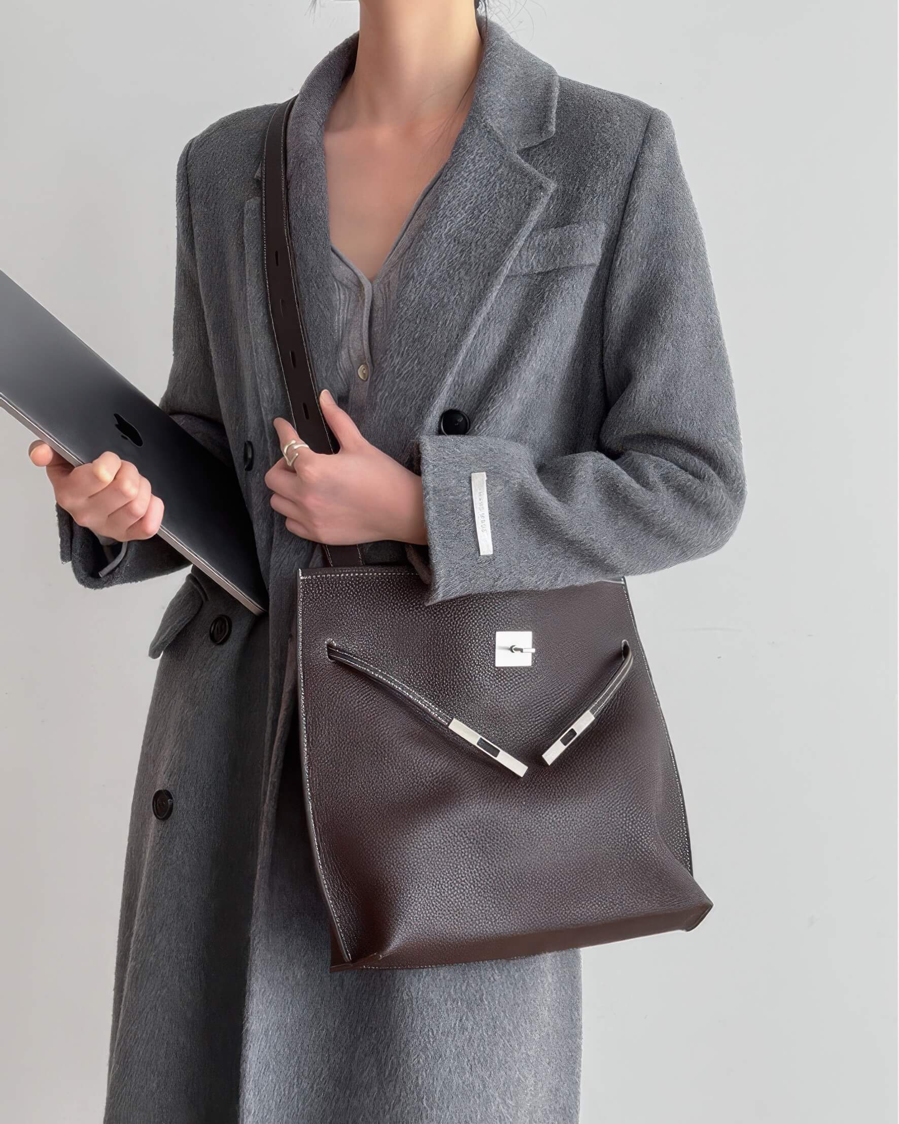 Side profile of a slim burgundy leather satchel with long shoulder straps.