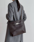 Front view of a rectangular wine red leather bag on a white background with a key pendant.