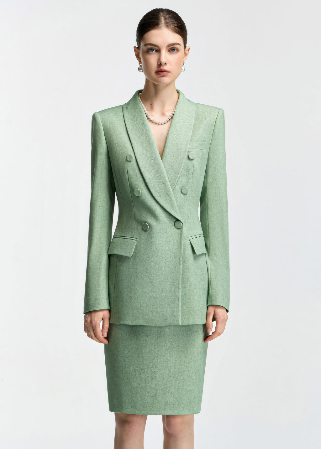 A front-facing, medium shot of the model wearing the mint green blazer, highlighting the double-breasted button detail, lapels, and pearl necklace.