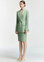 A full-body shot of the model standing at a three-quarter angle, showcasing the length of the blazer and the fit of the matching skirt.