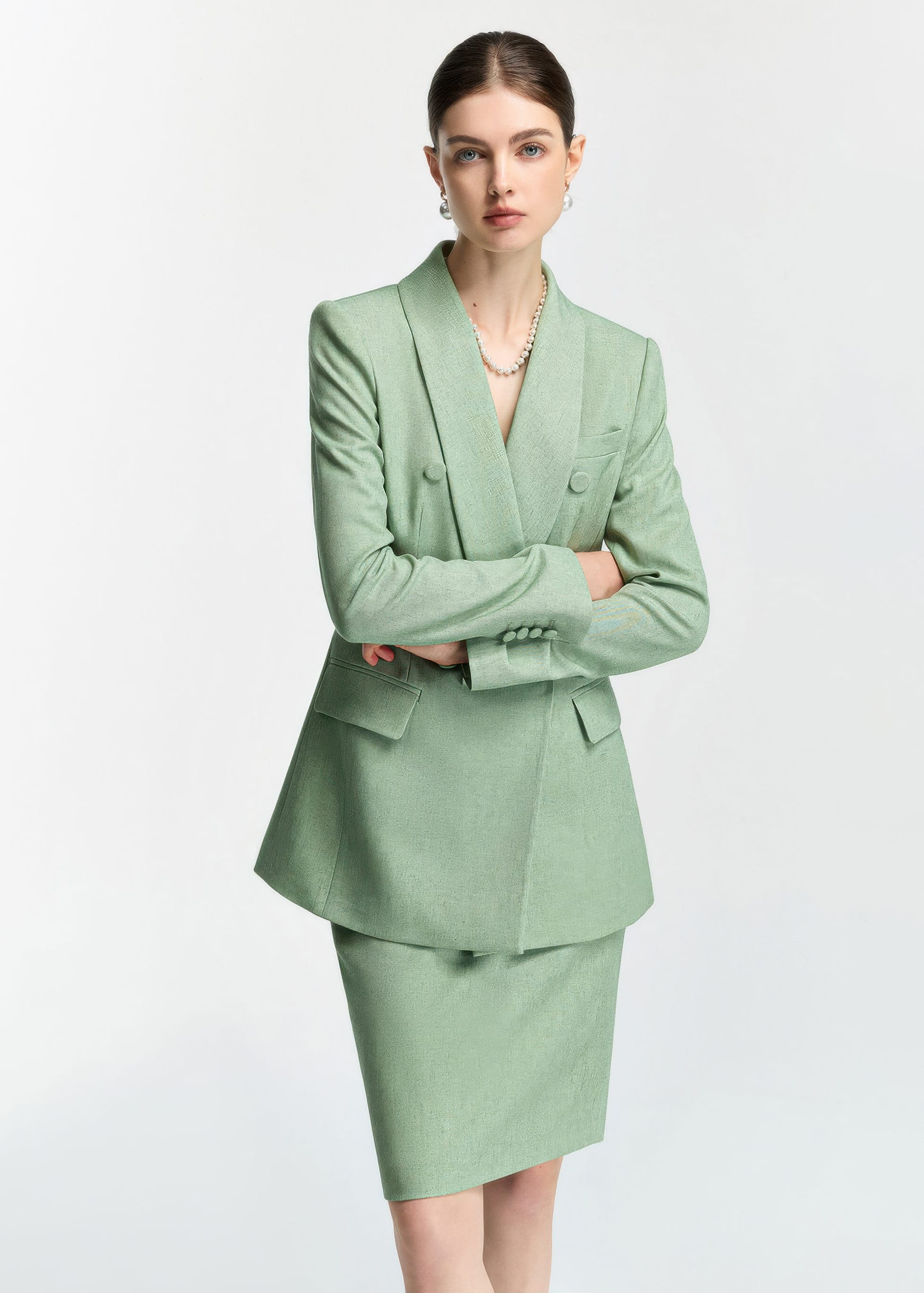 A medium shot of the model with her arms crossed, showing the sleeve button details and the structured shoulder design of the mint green blazer.