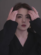 A video showcasing a pair of gold-toned concentric circle drop earrings. A model wears the earrings, tilting her head to show the light reflecting off the textured, spiral-etched surface and the modern vertical slit design.